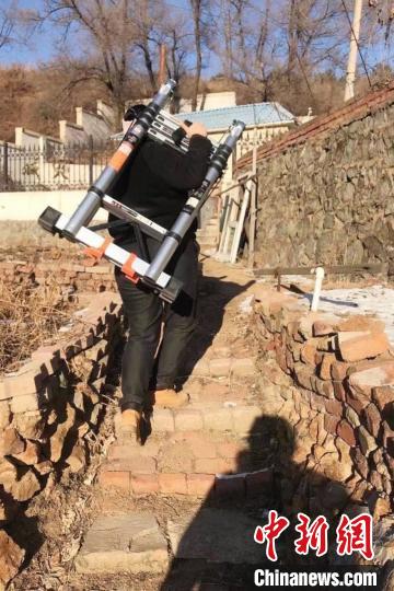 雷晨扛着仪器走路。辽宁省地震局供图