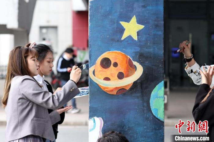大学生们在校园楼宇立柱上绘制航天图案。　泱波 摄