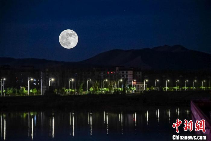 5月26日深夜，一轮超级圆月悬挂在敦煌党河风情线上。(图片为双重曝光)。　王斌银 摄