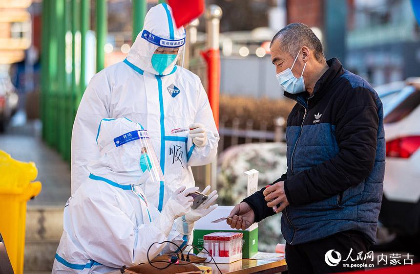 在呼和浩特市玉泉区清泉街社区临时核酸采样点，党员志愿者为市民进行个人信息采集。丁根厚摄
