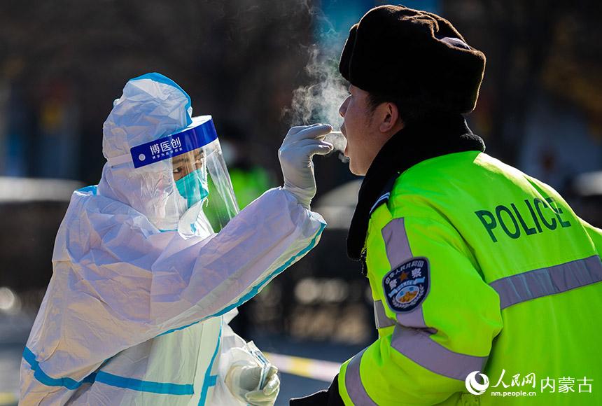 在呼和浩特市玉泉区小召街道五塔寺广场临时核酸采样点，医护人员为执勤民警进行核酸采样。丁根厚摄